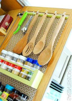 wooden utensils and spoons hanging from hooks on a kitchen cabinet door shelf