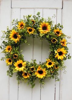 a wreath with sunflowers hanging on a white door