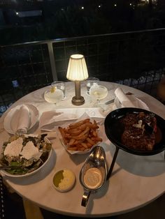 a table topped with lots of food next to a lamp on top of a table