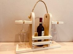 a wine bottle holder with two bottles in it and a glass on the table next to it