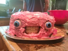 a pink cake with googly eyes and teeth