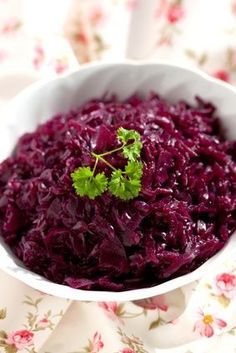 a white bowl filled with red cabbage on top of a wooden cutting board