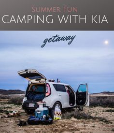 a car with its trunk open sitting in the middle of a dirt field next to a tent