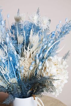 a white vase filled with blue and white flowers