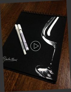 a black notebook with white writing on it and two pens sitting next to each other