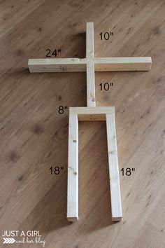 a wooden cross sitting on top of a wood floor next to a ruler and measuring tape