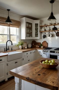 a bowl of green apples sitting on top of a wooden table in a kitchen next to an oven