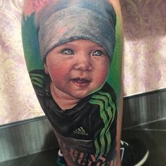 a close up of a person's leg with a tattoo on it and an image of a baby wearing a beanie