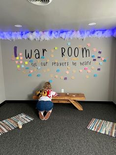 a woman sitting on top of a wooden bench in front of a wall with post it notes