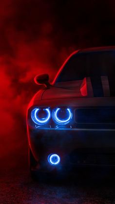 the front end of a car with its lights on and fog in the air behind it