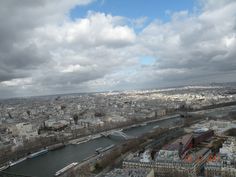 an aerial view of the city of paris with clouds in the sky and water below