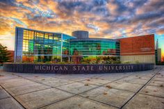 the michigan state university campus in front of a colorful sky with clouds and trees on it