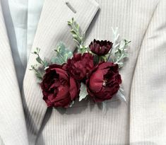 a man in a suit with red flowers on his lapel flower pin, which is attached to the lapel of his jacket