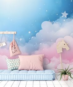 there is a blue couch with pink pillows in front of the stars and clouds wall mural