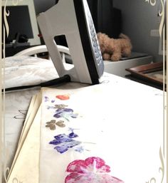 an ironing board with flowers on it next to a book and a teddy bear