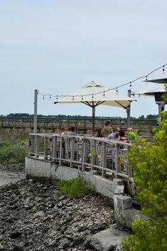 people are sitting at an outdoor table with umbrellas over them and some rocks in the foreground