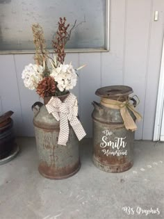 two metal containers with flowers in them sitting on the ground next to a wall and door