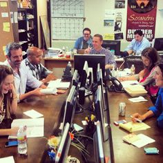 a group of people sitting at a table with papers and pens in front of them