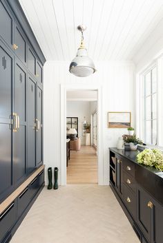 a long hallway leading to a kitchen with black cabinets and drawers on either side of the room