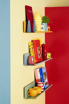 two shelves with books, cups and mugs on them against a red and yellow wall