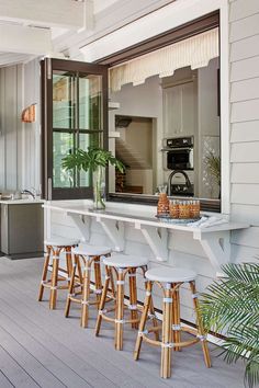 an outdoor bar with stools and a potted plant on the counter next to it