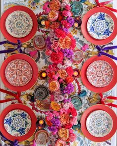 the table is decorated with colorful plates and flowers on top of each plate, along with ribbons