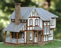 a small model house sitting on top of a green field