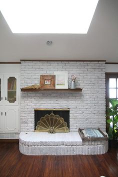 a living room with a white brick fireplace and wooden floors