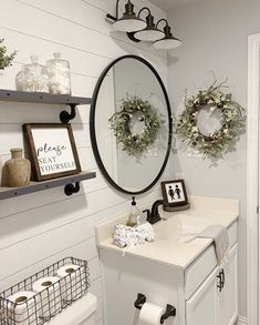 a white bathroom with two wreaths on the wall