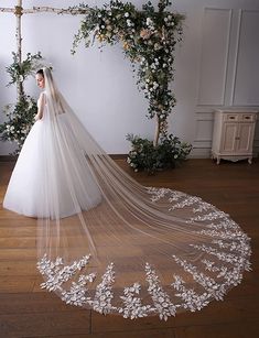 a woman in a white wedding dress standing on a wooden floor with her veil pulled back