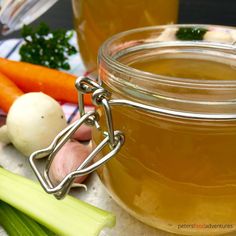 a jar filled with liquid sitting next to some vegetables