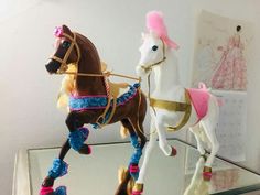 two toy horses that are on top of a glass shelf in front of a mirror