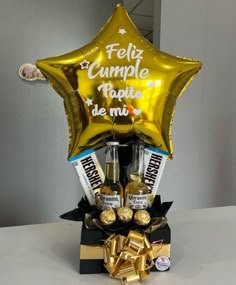 a golden star balloon and some chocolates in a black box with gold foil balloons