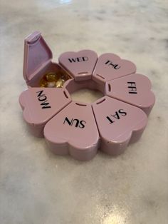 a pink heart shaped box with words written on it and two gold rings in the middle