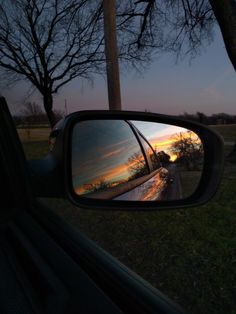 the rear view mirror of a car with trees in the back ground and sky reflected in it