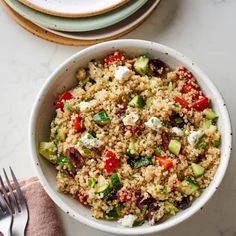 a white bowl filled with food next to two plates