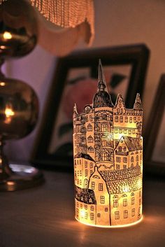 a lit candle is sitting on a table next to some pictures and a lamp shade