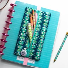 an open notebook with pens and pencils on it next to a pair of eyeglasses