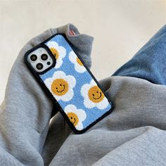 a cell phone case with smiley faces on it sitting on someone's lap,