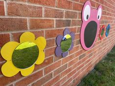 three flower shaped mirrors mounted to the side of a brick wall next to a grass field