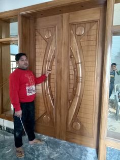 a man standing in front of a wooden door with carvings on the doors and side panels