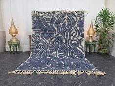 a blue and white rug on the floor next to two small tables with plants in them