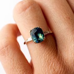 a woman's hand with a ring on it and a blue stone in the middle