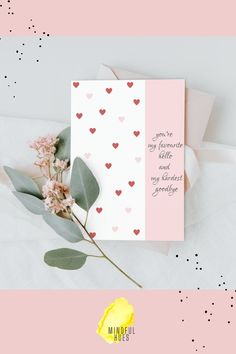 a pink and white card with hearts on it, next to some eucalyptus leaves and flowers