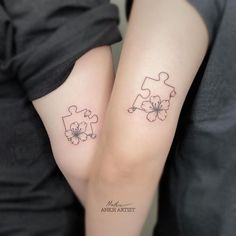 two people with matching tattoos on their arms holding each other's hands, one has a puzzle piece and the other has a flower