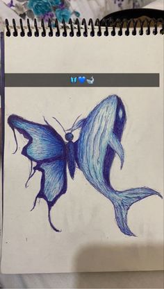 a drawing of a blue butterfly on top of a notebook