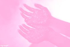 two hands with glitter on them are touching each other's palms against a pink background