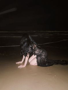 a woman kneeling on the beach at night with her head in the sand and arms behind her back