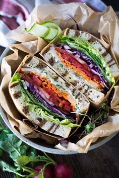 a sandwich with lettuce, carrots and other vegetables in a paper wrapper