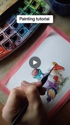 a person is painting with watercolors on paper and using a pen to draw the image